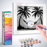 Paint by Numbers kit Tropical Calm Black and White with paint pots and brush, featuring a tranquil scene of palm trees and hammock.