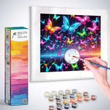 Person painting a vibrant butterfly dance paint-by-numbers kit with colorful butterflies on canvas, surrounded by painting supplies and a box labeled 