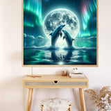 Painting by numbers kit showing dolphins dancing under a full moon, displayed on a minimalist wooden desk setup