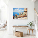 Painting of a Mediterranean coastal view on a terrace with chairs, vibrant flowers in orange and lilac tones, and a view of the blue sea.