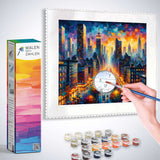 Person painting a vibrant cityscape with Malen nach Zahlen kit, showing paint pots, brush, and a canvas with numbered sections.