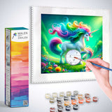 Painting by numbers set with colorful unicorn design, hand applying paint to canvas, surrounded by paint pots and box labeled Malen nach Zahlen.
