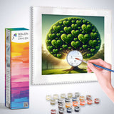 Painting by numbers kit - Herzensbaum: Zauber der Natur with heart-shaped tree, color palettes, and paintbrush in hand while painting.