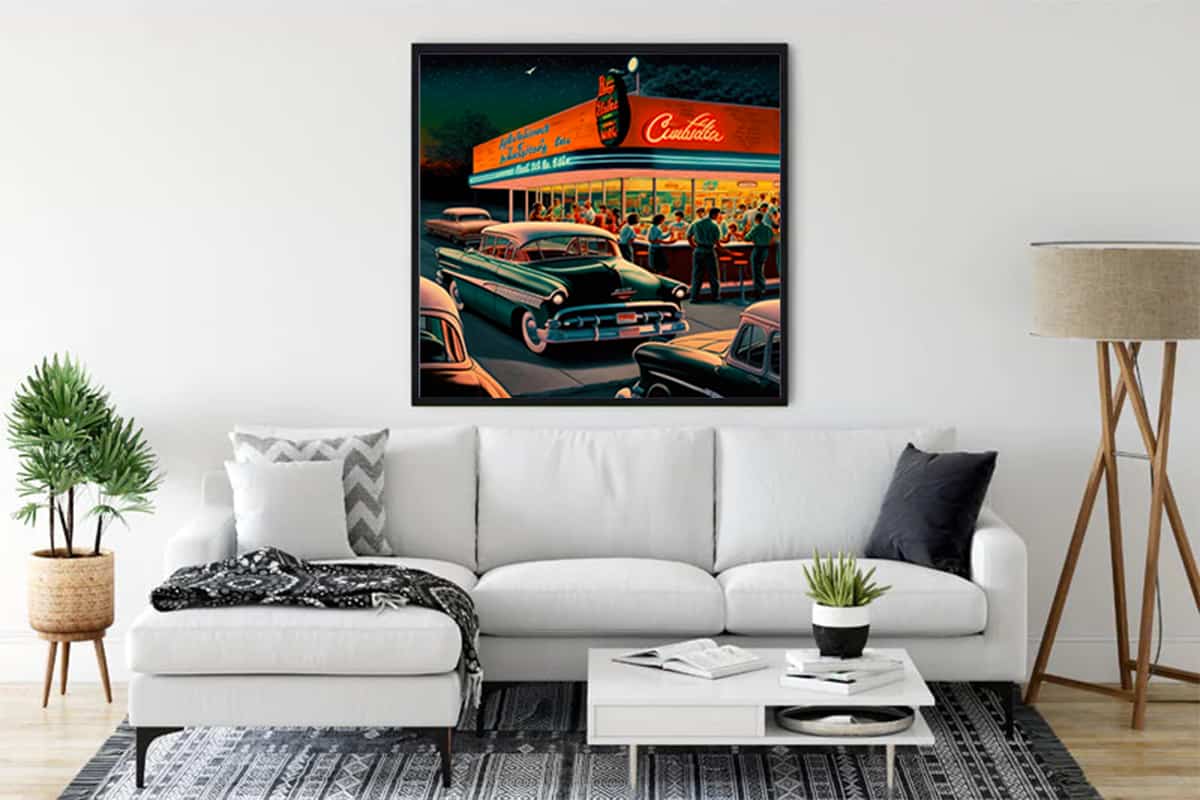 Painting of a vintage gas station with classic cars hung above a white couch in a modern living room