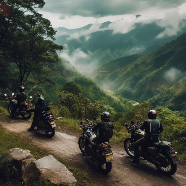 Four motorcyclists riding through scenic mountain landscape surrounded by lush green hills and misty clouds