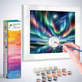 Malen nach Zahlen - Polarlichter der Stille kit showing hand painting colorful northern lights with paint pots and brush.