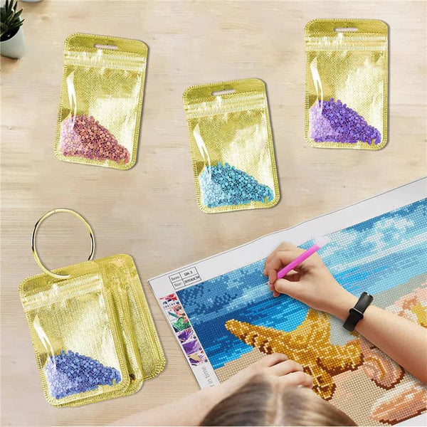 Diamond Painting set with ring storage and colorful diamond bags, creating detailed artwork with golden tool on a table.