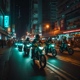 Gruppe von Motorradfahrern bei Nacht in einer belebten Stadtstraße, beleuchtet von Scheinwerfern und Neonlichtern.