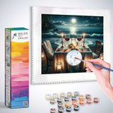 Paint by Numbers kit - Moonlight Serenade with paints, brushes, and framed artwork of a serene seaside dinner scene under a full moon.