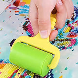 Hand using green roller on diamond painting canvas with colorful acrylic diamonds