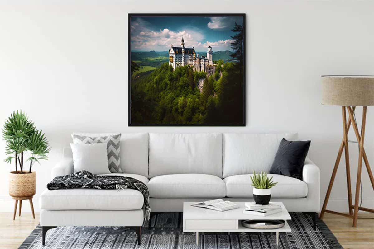 Living room with a framed painting of Schloss Neuschwanstein surrounded by greenery above a white couch.
